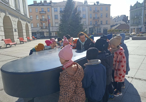 Dzieci po wizycie w Ratuszu śpiewają piosenkę przy fortepianie.